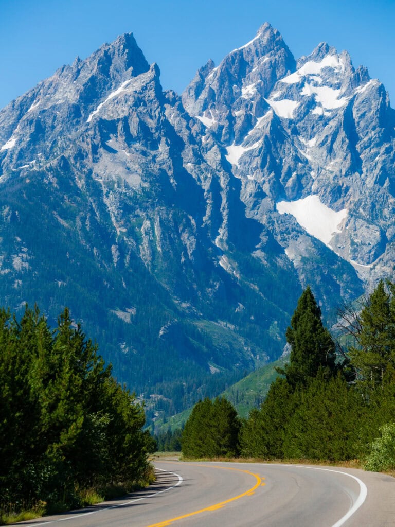 Close view of jagged Teton peaks draped in snow above dense pine forest