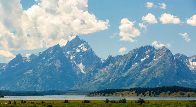 Broad Teton peaks under a partly cloudy summer sky