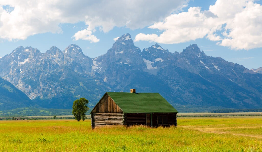 Historic wooden barn on flat sagebrush flats with the Teton Range behind