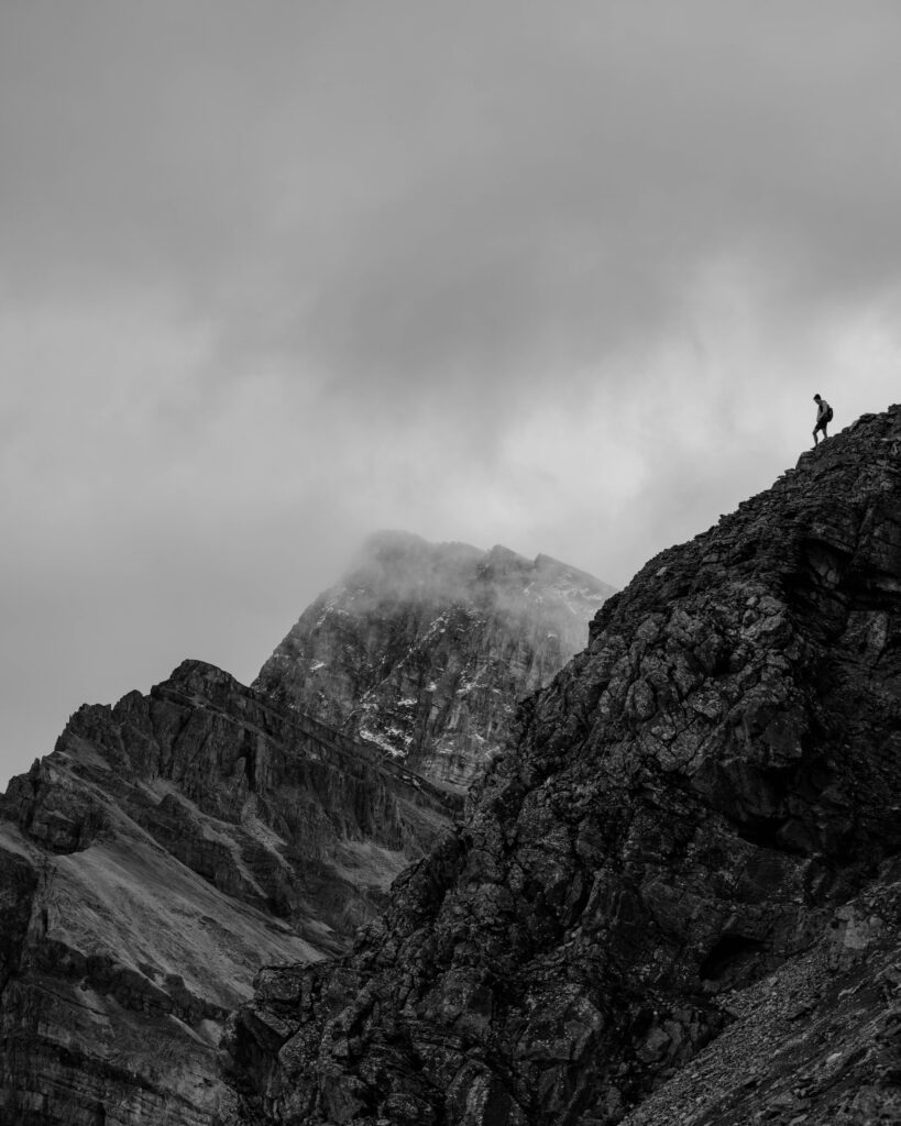 black and white image of a hiker standing on the edge of a cliff