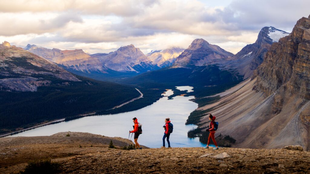 three hikers walk on the rocks in canada above a lake