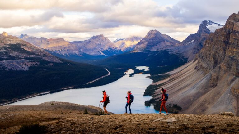 three hikers walk on the rocks in canada above a lake
