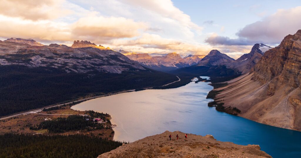 a lake surrounded by mountains during sunset