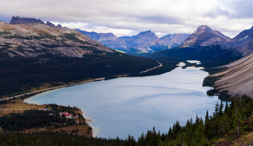 a lake below with mountains and a road next to it on the left