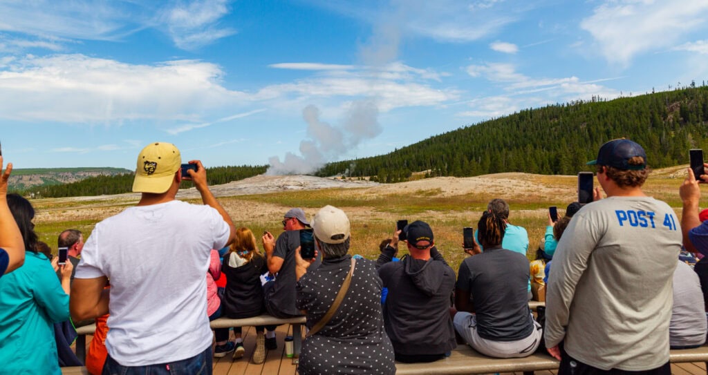yellowstone visitors watching and filming old faithful going off