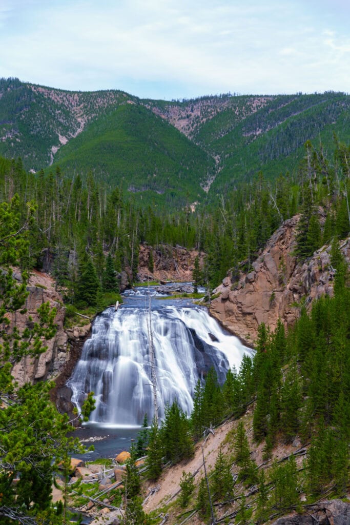 Forested valley with a distant waterfall dropping into green canyon