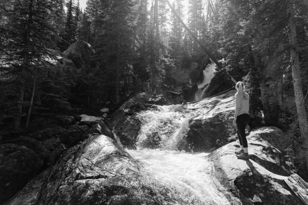 a female hiker looks out a willow creek falls