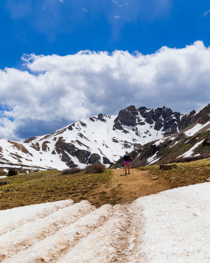Wide view of a snow-capped mountain range with dramatic clouds over Herman Gulch Trail