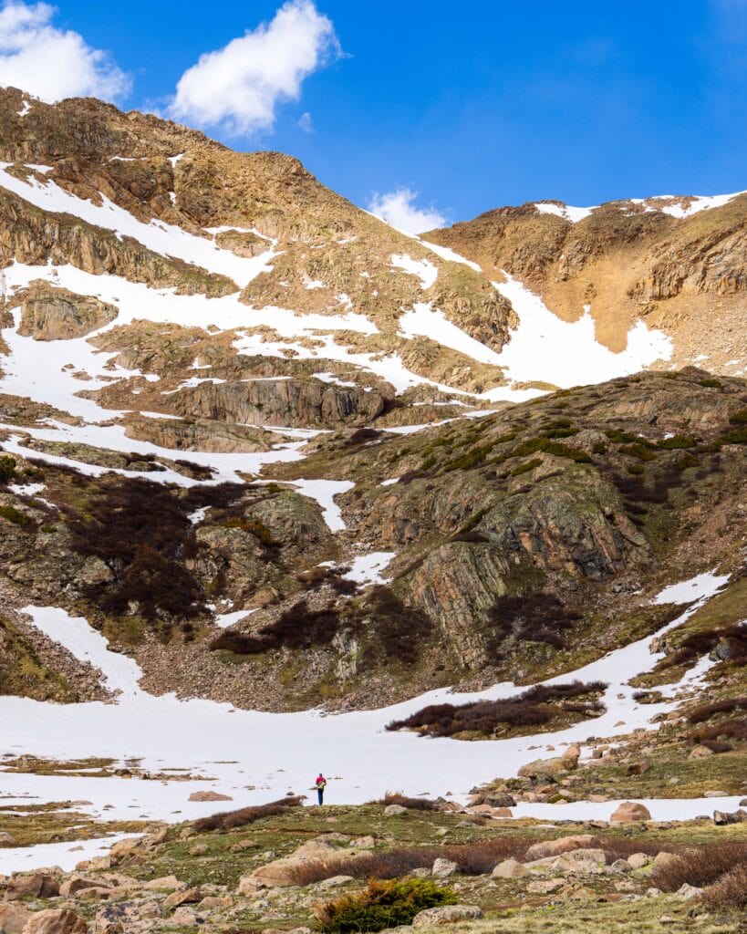 Rocky mountain ridge streaked with snow above an alpine basin on Herman Gulch Trail