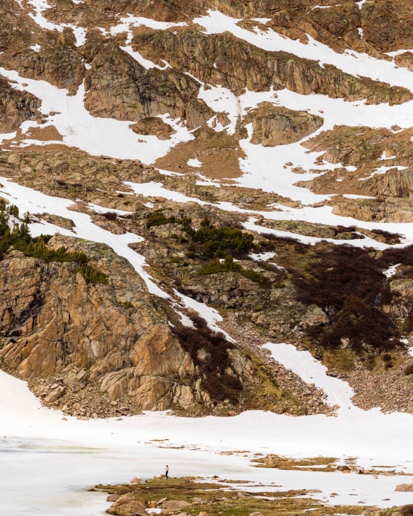 Snow patches scattered across a rocky mountain slope under a blue sky, Herman Gulch Trail
