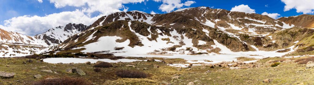 Panorama view of a rocky alpine ridge with patches of snow under a blue sky, Herman Gulch Trail, Colorado