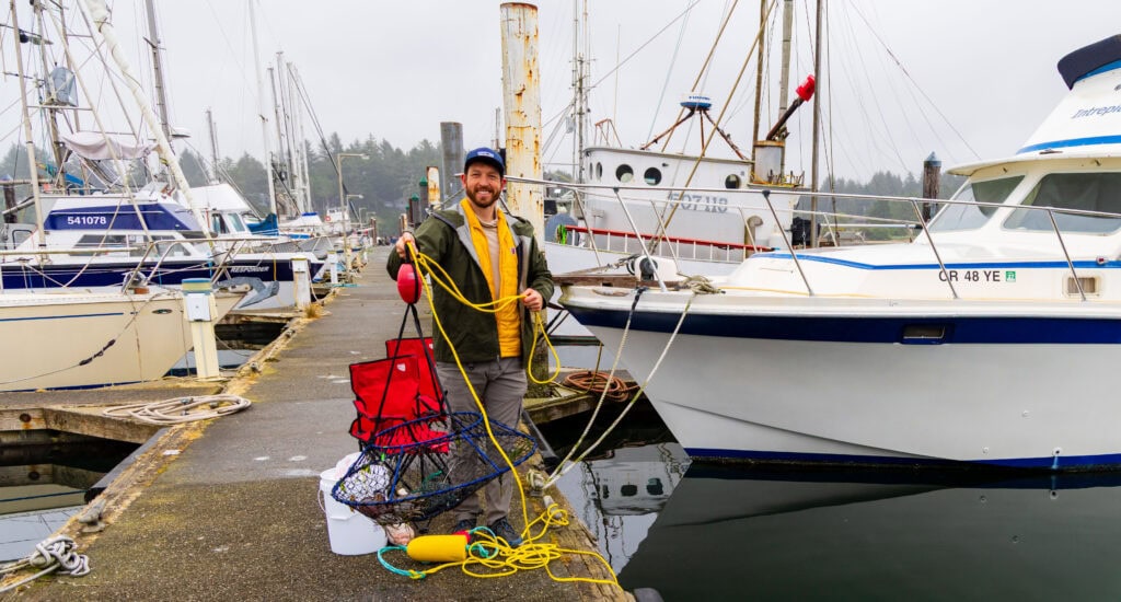 the author holding up a crab pot on a dock