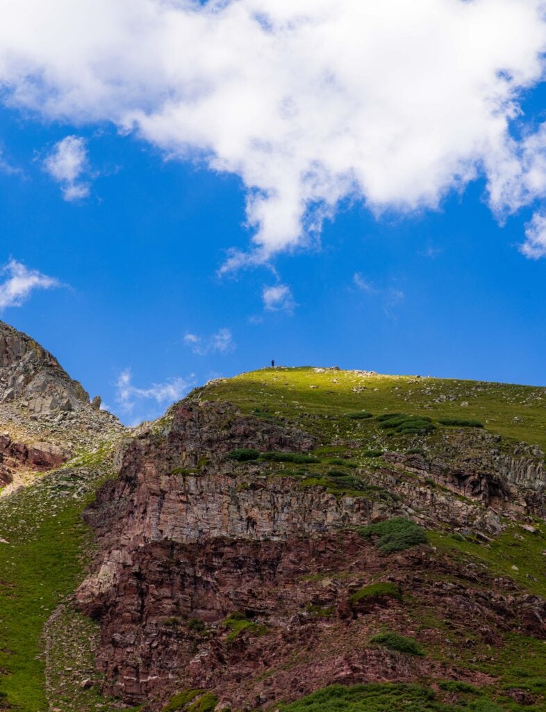 buckskin pass with a single hiker on top with clouds above