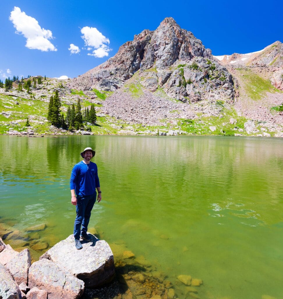 a hiker smiles at the camera in front of gore lake