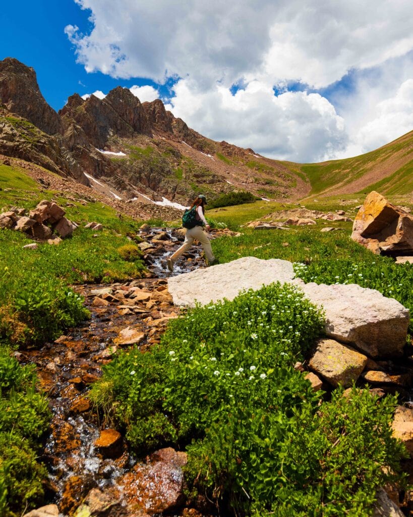 a hiker crosses a small creek near snow lake in colorado's gore range