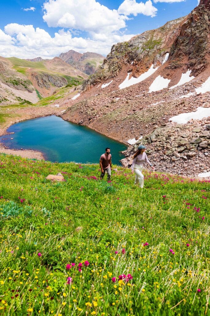 hikers walk on a trail above snow lake in the gore range
