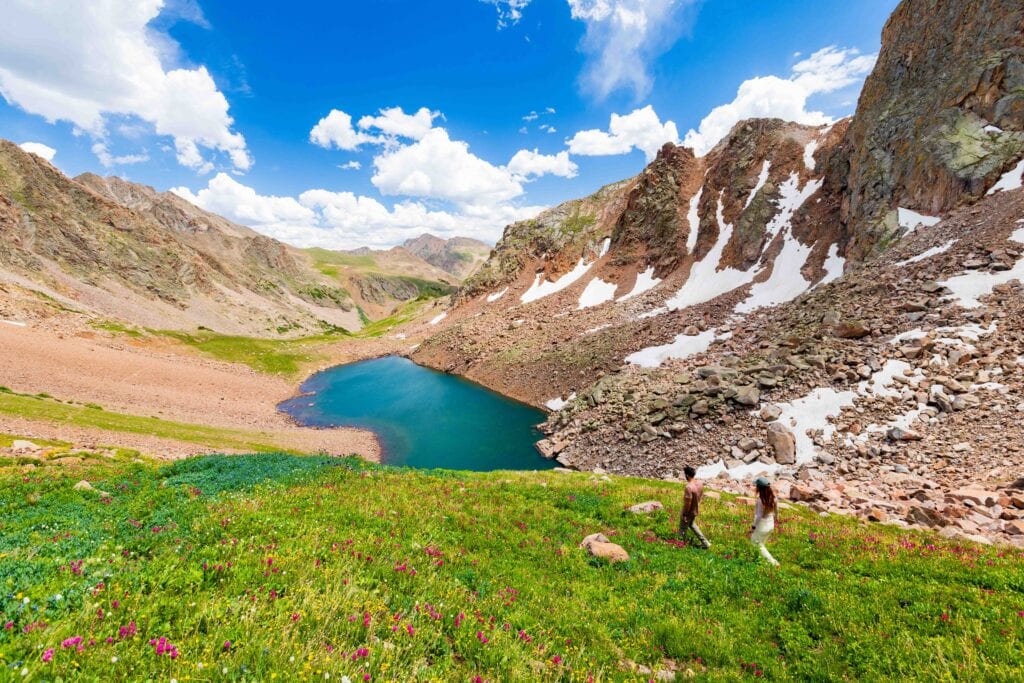 hikers walk on a trail above snow lake in the gore range