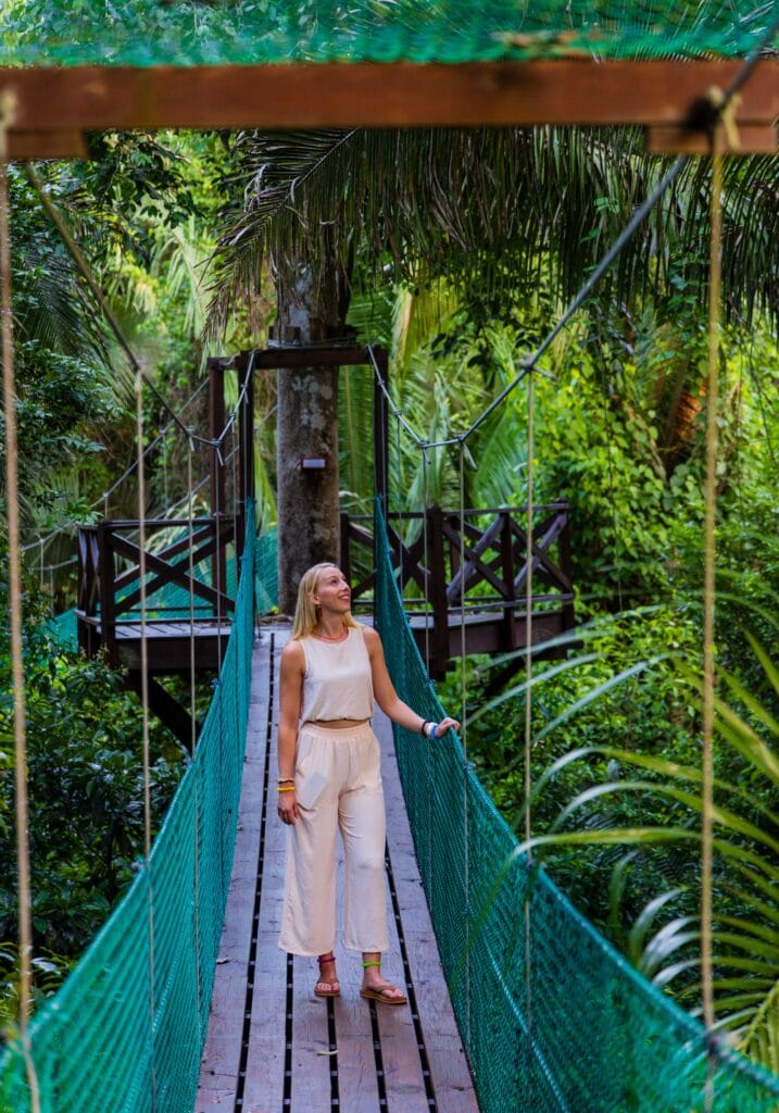 a woman walks on a hanging bridge in belize