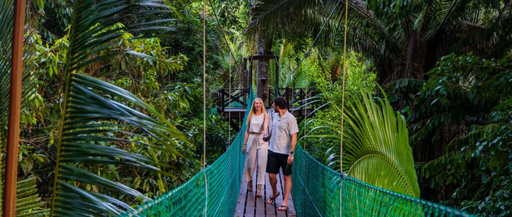 a couple walks on a hanging bridge in belize