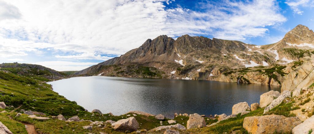 panorama of blue lake with clouds and mountain peaks