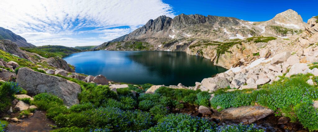 wide panorama of blue lake with clouds and mountain peaks