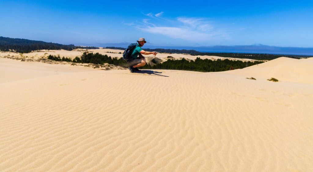 a hiker picks up sand on the oregon dunes