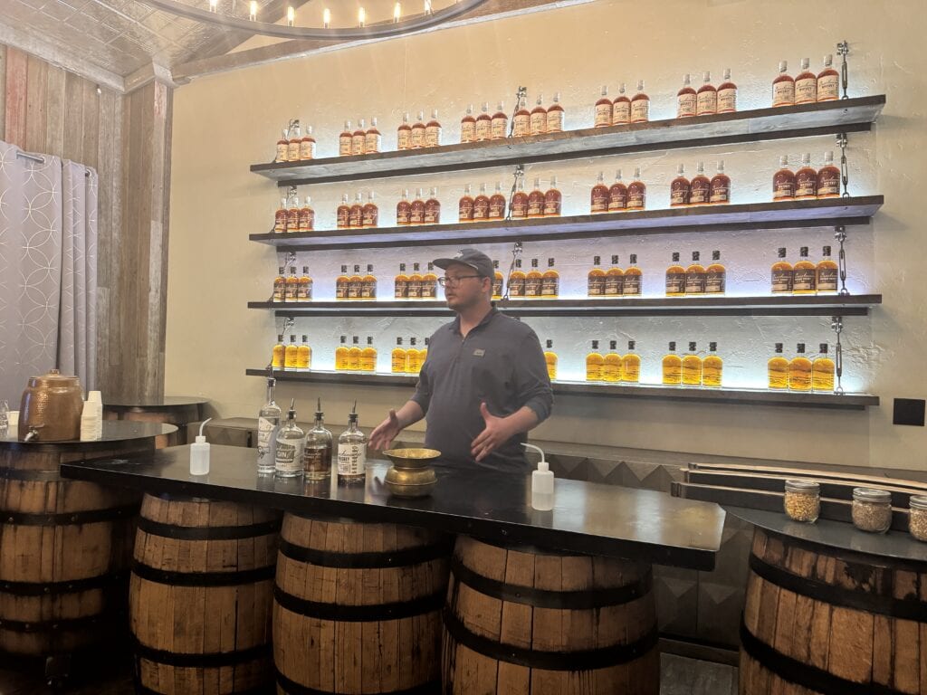 a man stands in front of a table at the breckenridge distillery talking about whiskey tastings