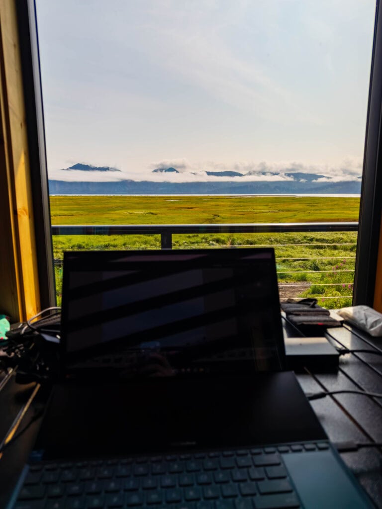 a laptop and a window looking out to chinitna bay in alaska