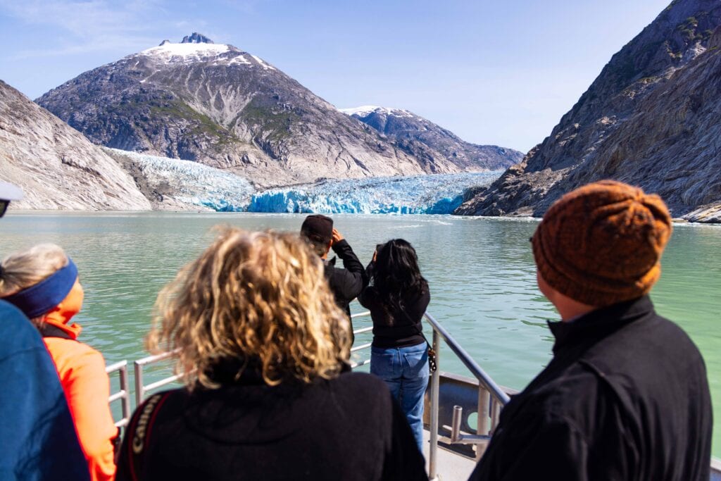 toursts look out at the dawes glacier as the boat slowly approaches