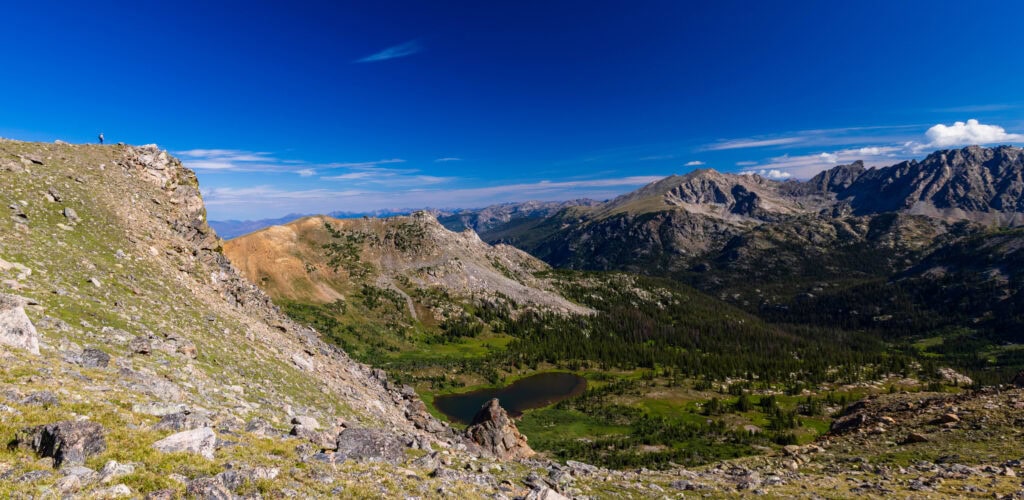 looking east from arapaho pass with a hiker on an edge way above caribou lake