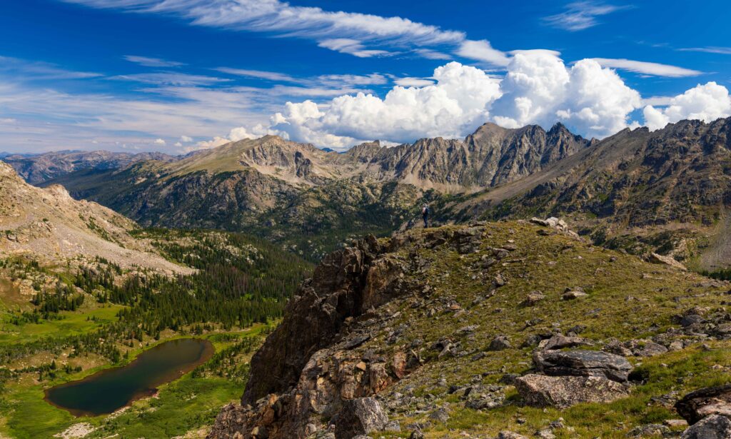 a hiker on the edge with caribou lake below - taken from arapaho pass
