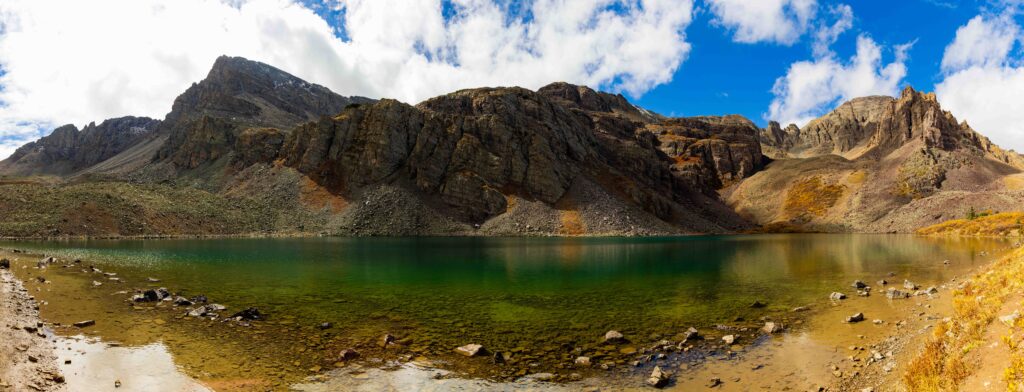 panorama of cathedral lake in colorado with tall mountains and fall colors