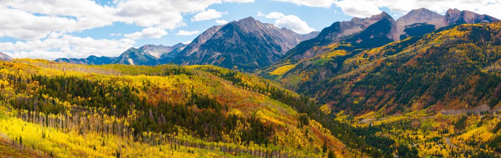 fall colors lining the slopes with a creek and mountains in view