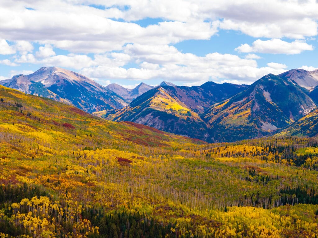 fall colors lining the slopes with a creek and mountains in view