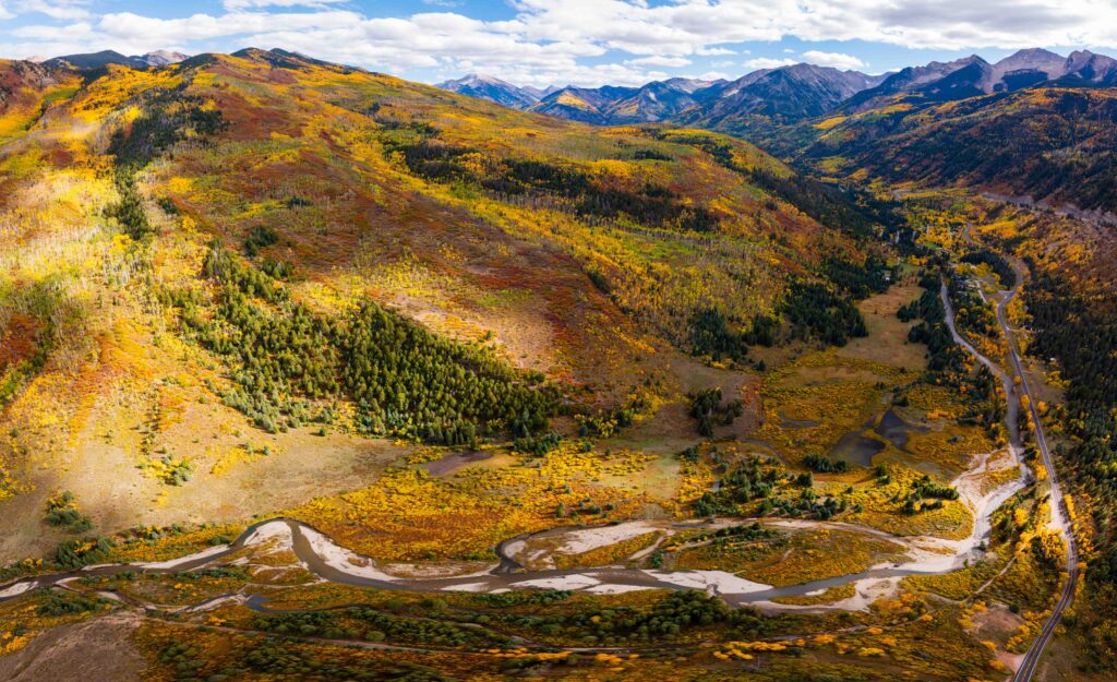 fall colors lining the slopes with a creek and mountains in view