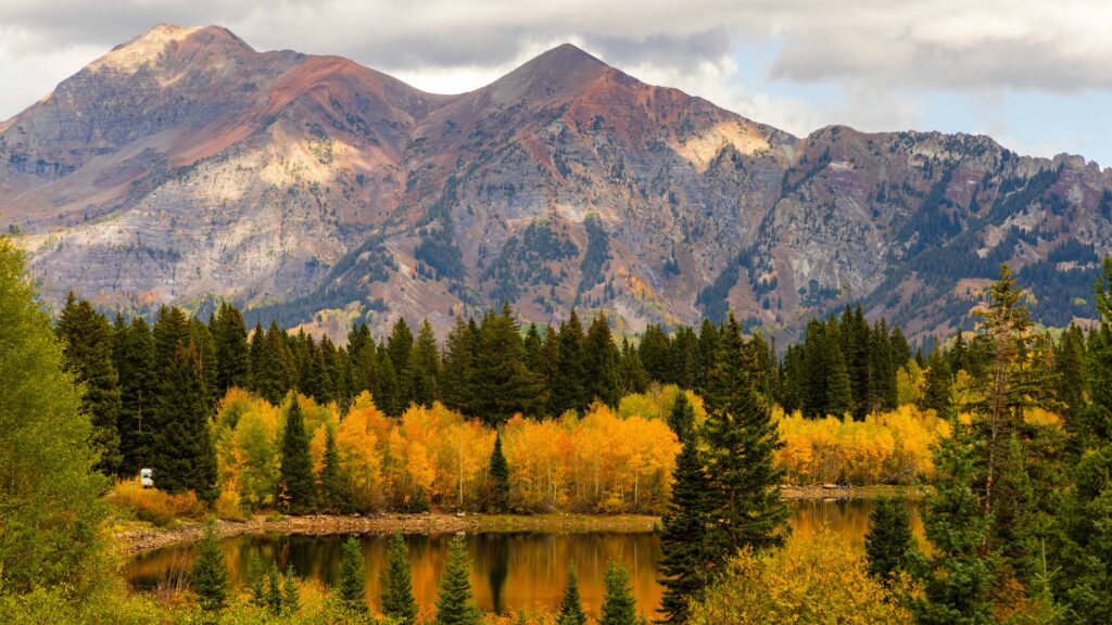 a mountain and clouds with a lake and trees below