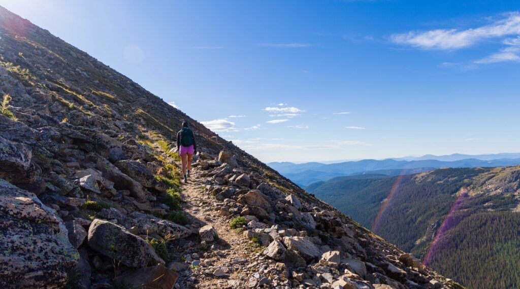 a hiker on the trail with mountains in the distance
