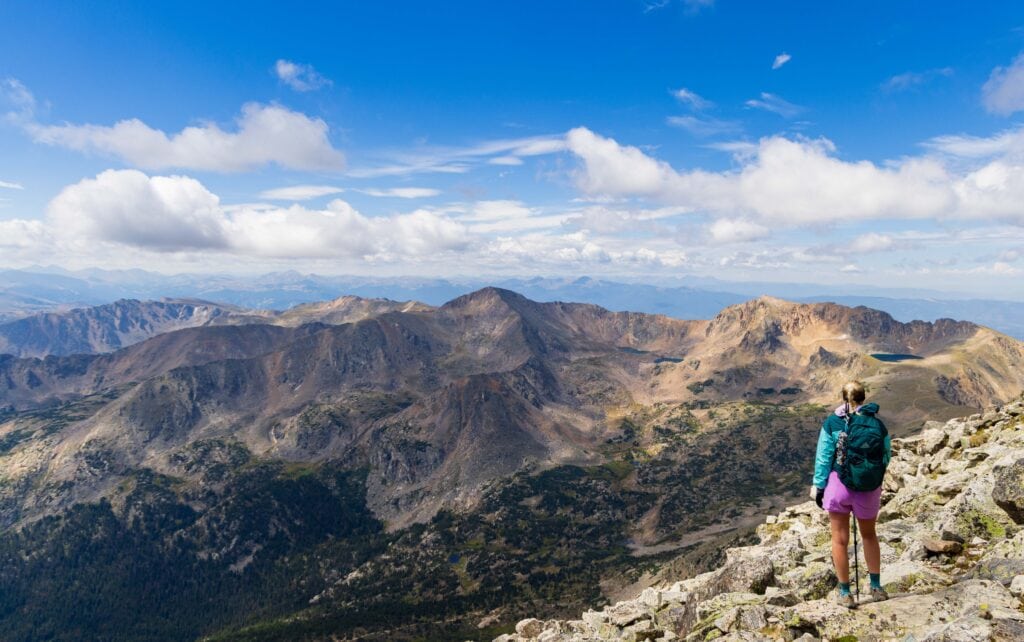 a hiker looks out from the rock field below south arapaho peak