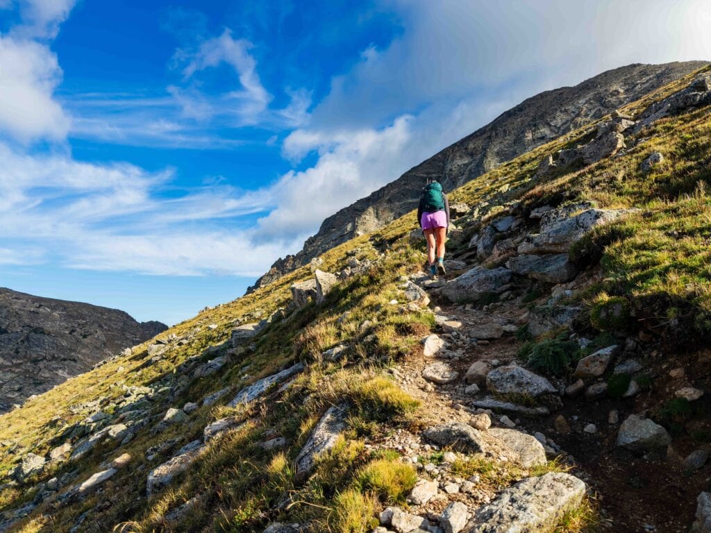 hikers on a trail in colorado with blue sky above