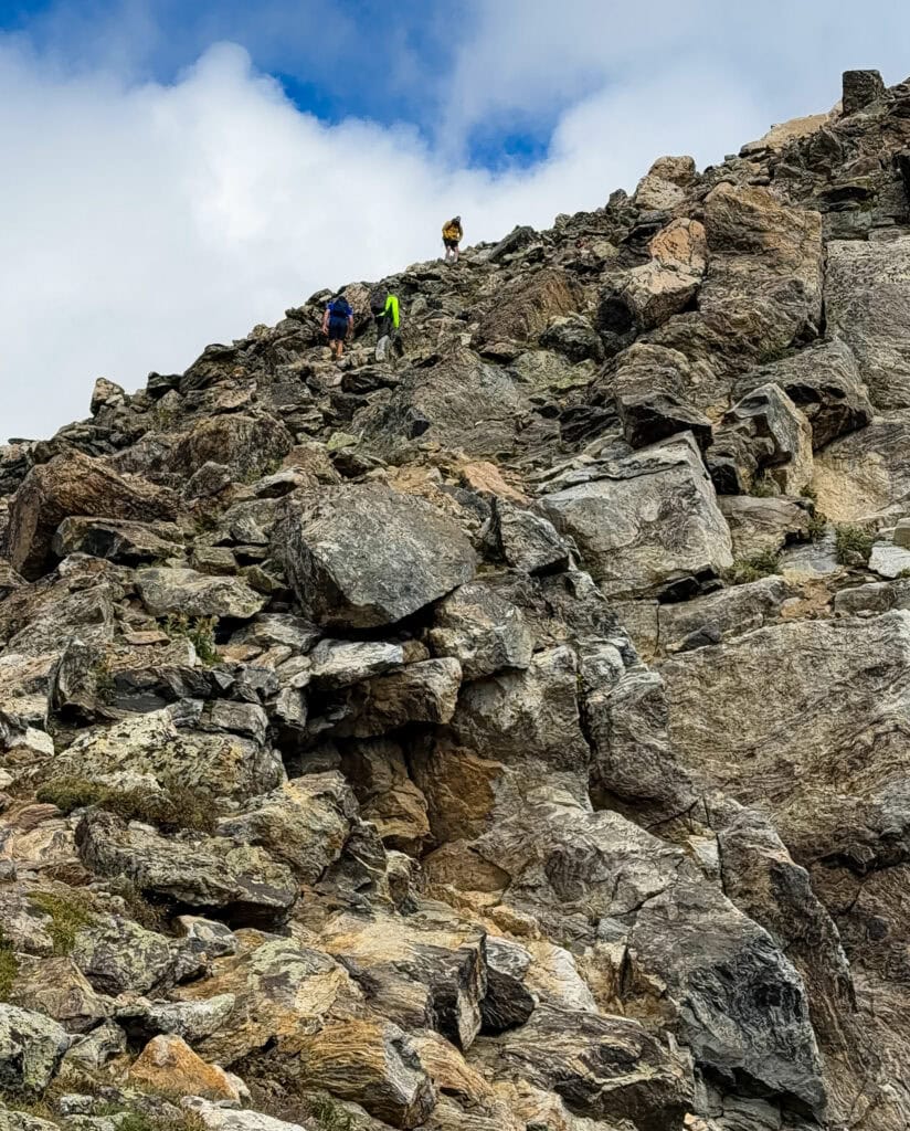 hikers going up the rock field on a mountain