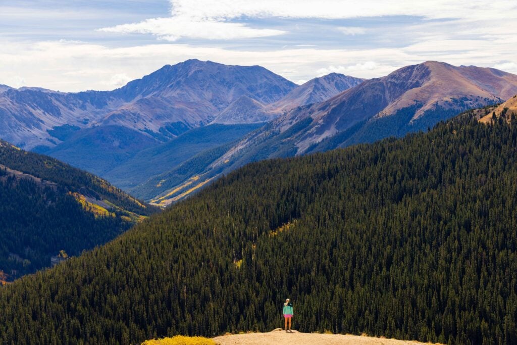 a woman hiker stands on the edge near independence pass in colorado