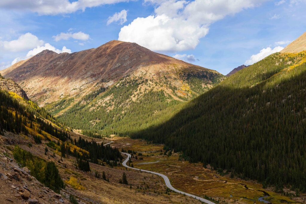 Paved mountain highway to independence pass colorado winding through a valley below rocky peaks