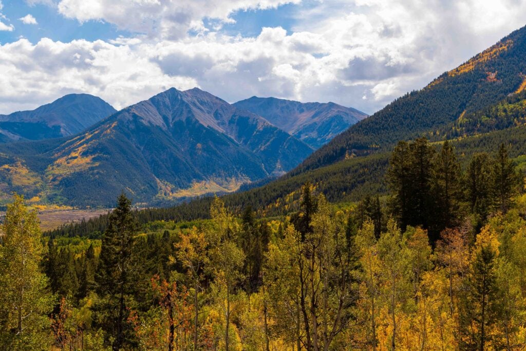 Forested valley and layered mountain peaks under a partly cloudy sky
