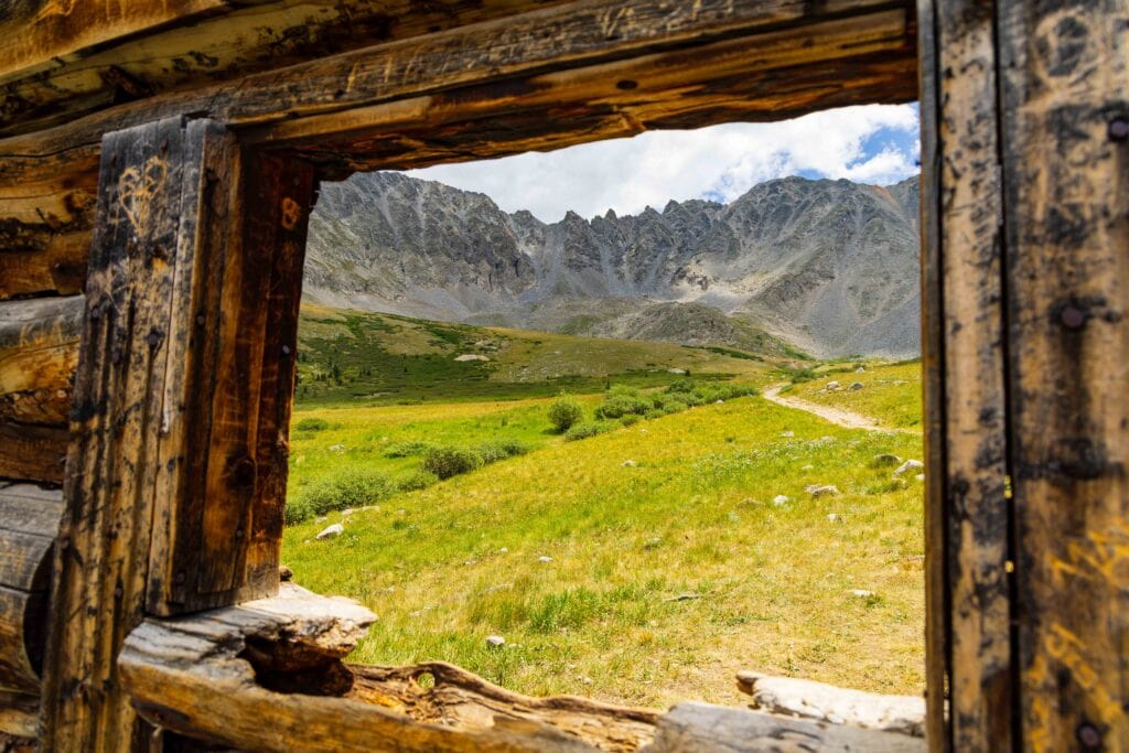 a cabin window with mountains in the background
