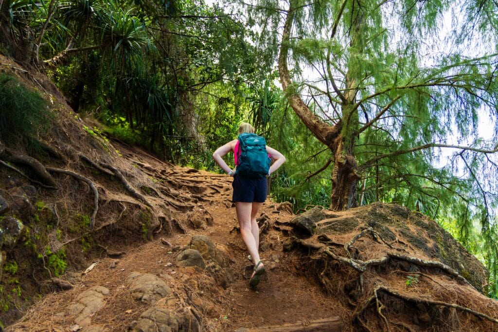 a woman puts her hands on her hips as she clips the steep muddy trail