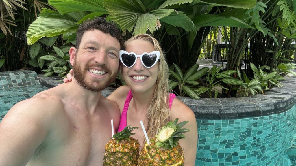 a man and woman in tabacon hot springs resort drinking out of a pineapple