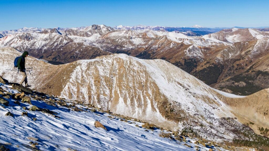a hiker walks down a snowy la plata peak in colorado