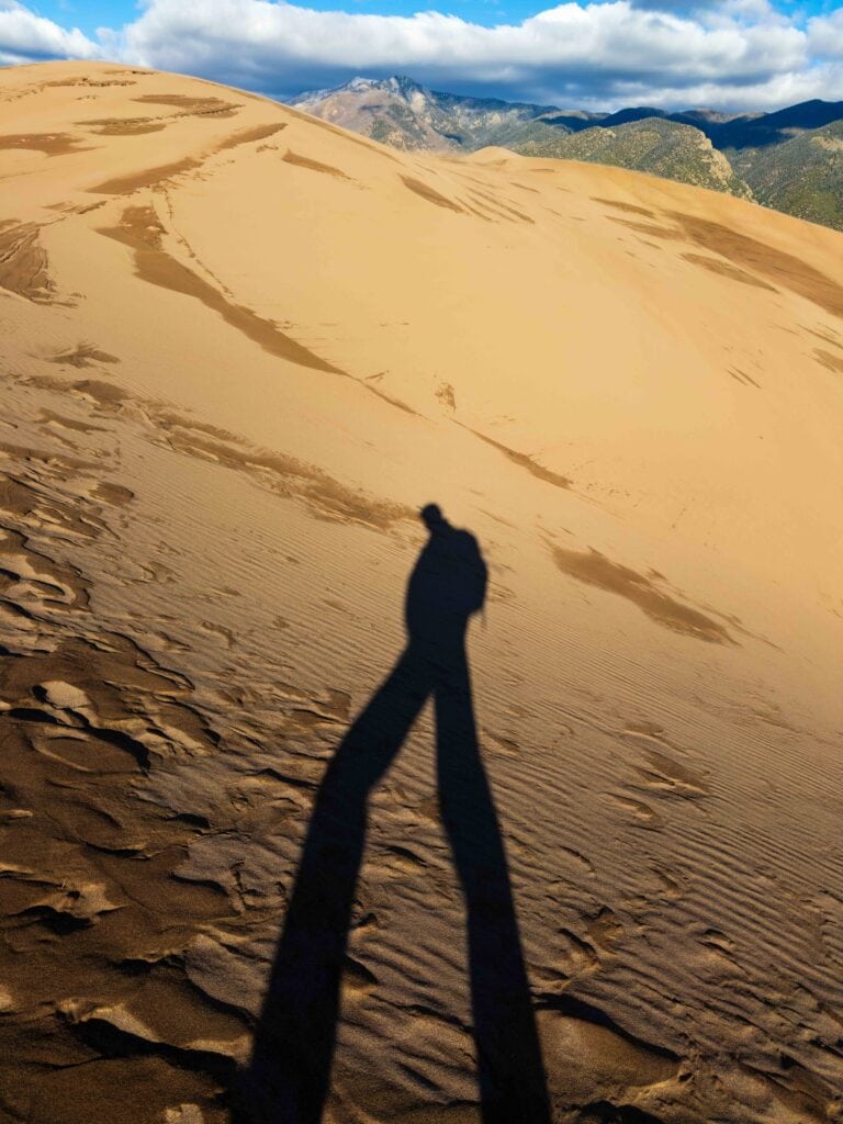 a hikers shadow on the sand dunes